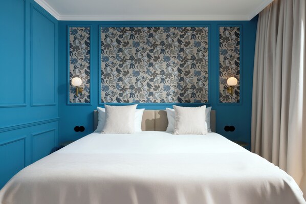 A hotel room with a large bed, blue walls, floral wallpaper, and two bedside lamps. - Água Hotels Lagos Bay (Lagos)