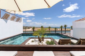A rooftop pool with lounge chairs and a view of the beach.