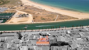 An aerial view of a coastal town with a beach, marina, and densely packed buildings. - Água Hotels Lagos Bay (Lagos)