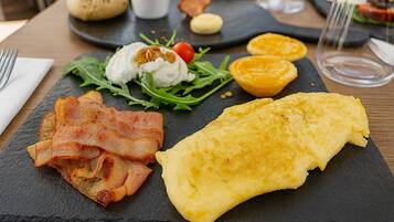 A breakfast plate with bacon, an omelette, and a salad on a slate board.