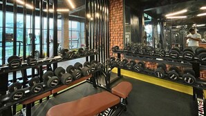 Une salle de sport équipée de supports à poids, d’haltères et d’un banc.
