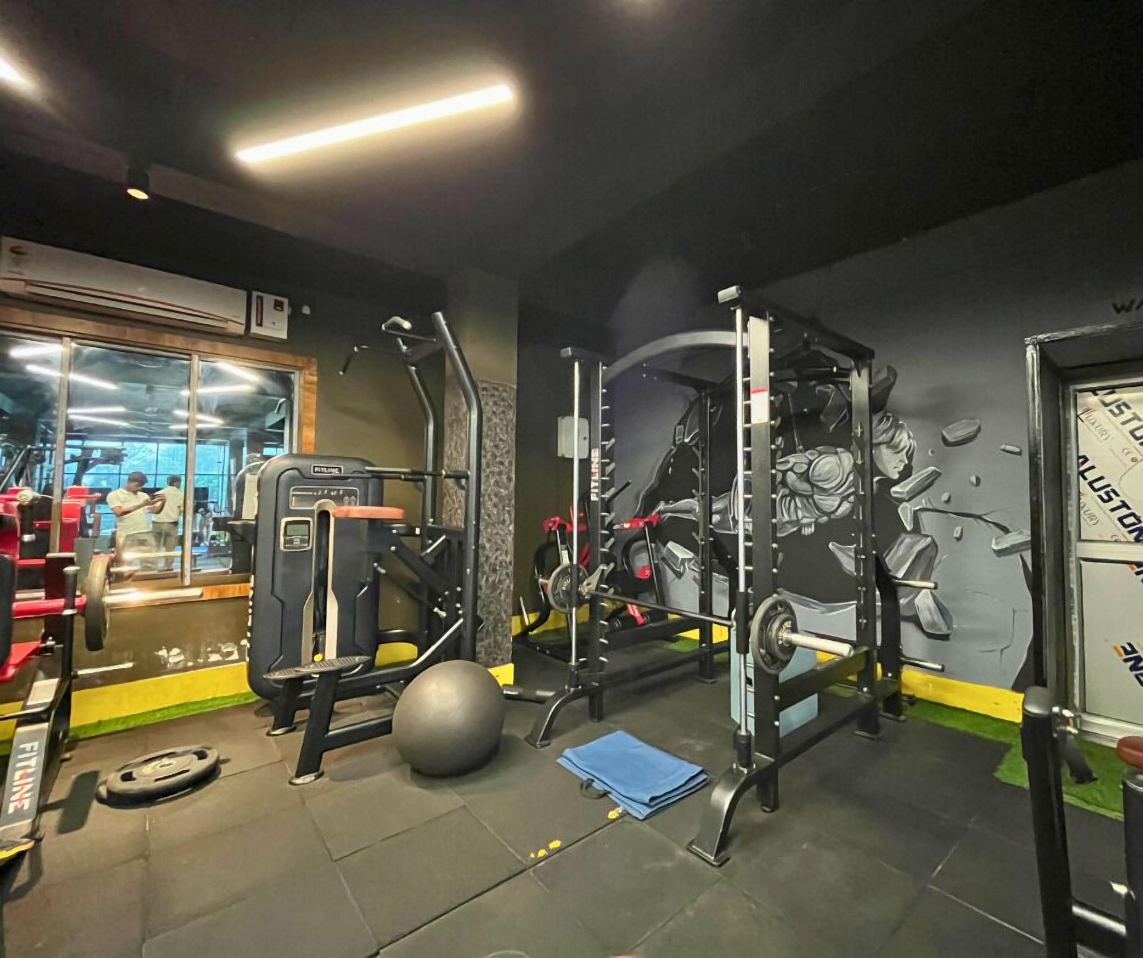 A gym with weightlifting equipment, a large exercise ball, and a mirror.