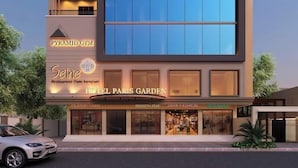 Un hôtel à plusieurs étages doté d’une grande façade en verre, d’une salle de sport située au dernier étage et de divers magasins au rez-de-chaussée.