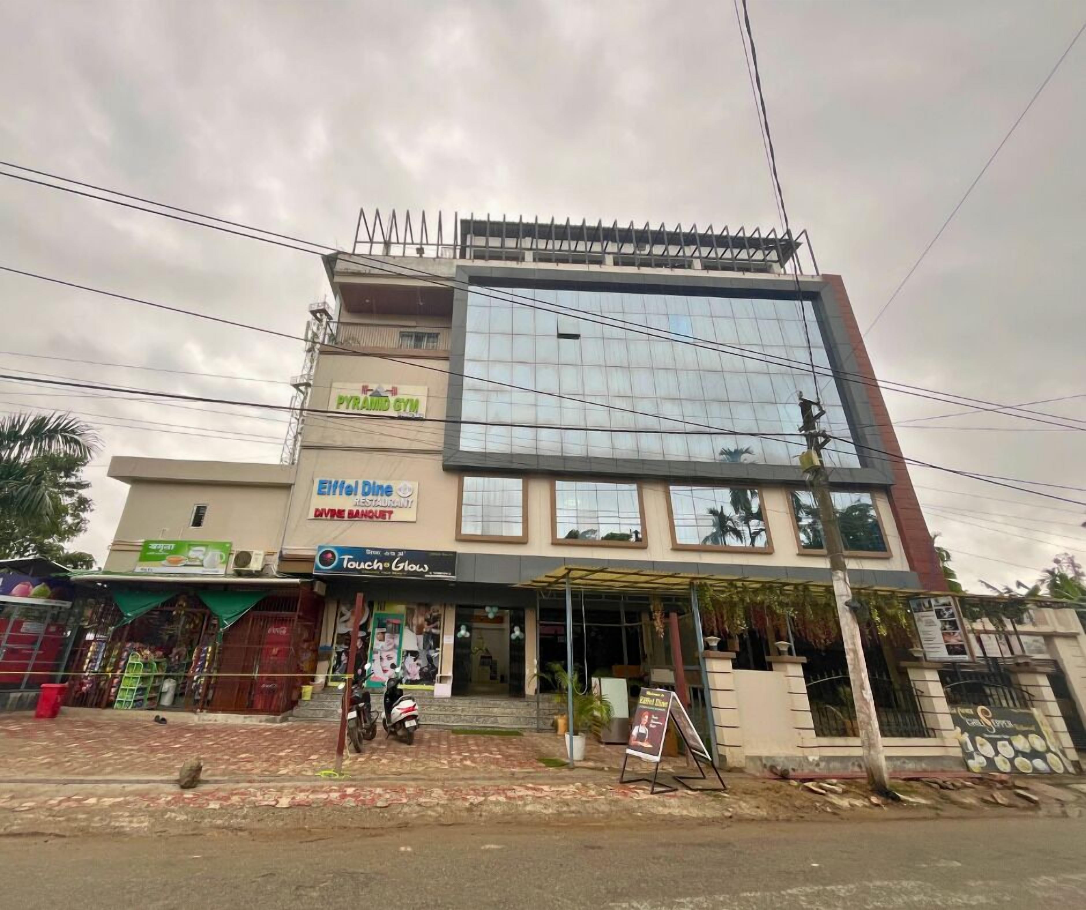 Edif ício de vários andares com academia no andar térreo, restaurante no segundo andar e fachada de vidro ampla nos andares superiores.