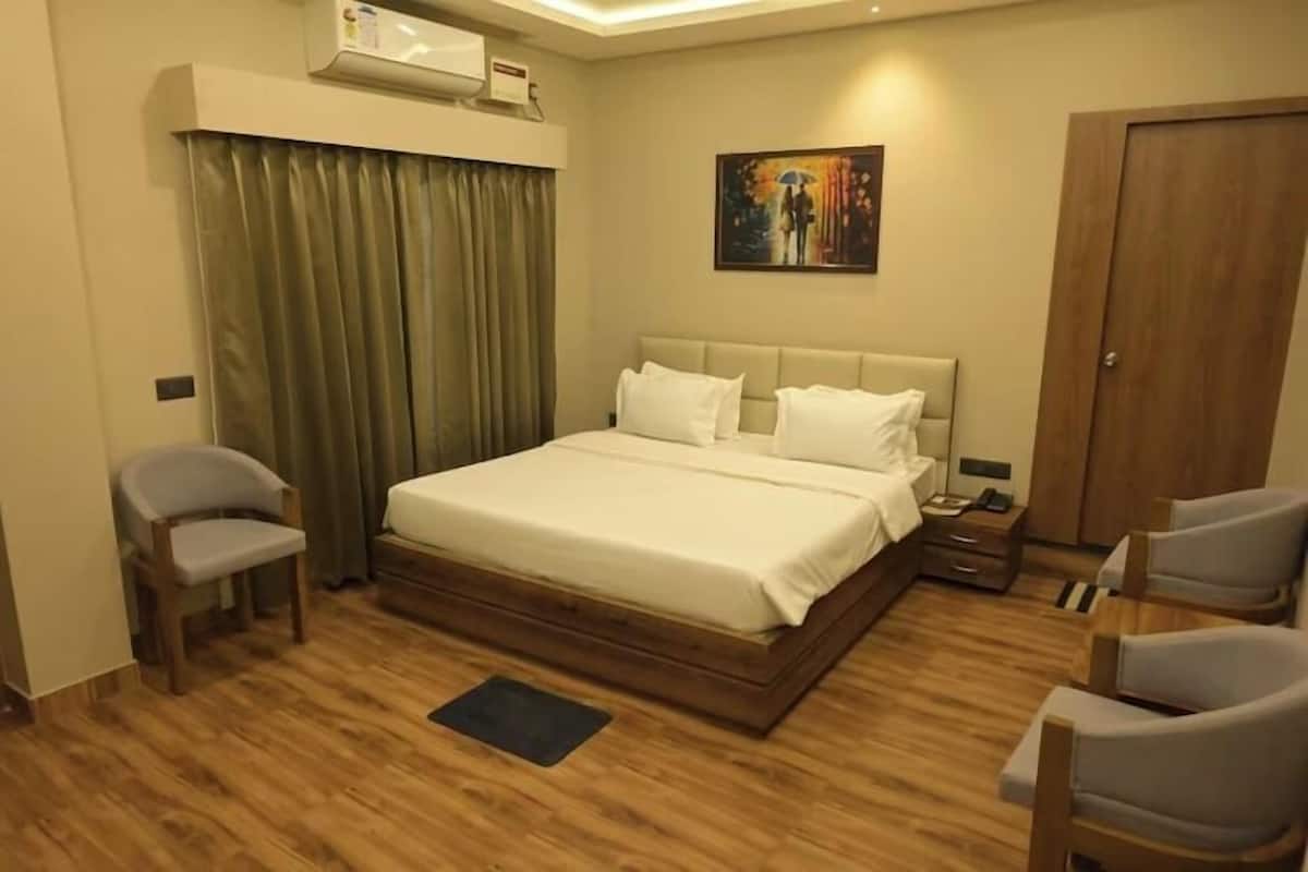A bedroom with a bed, a desk, a chair, a door, and a painting on the wall.
