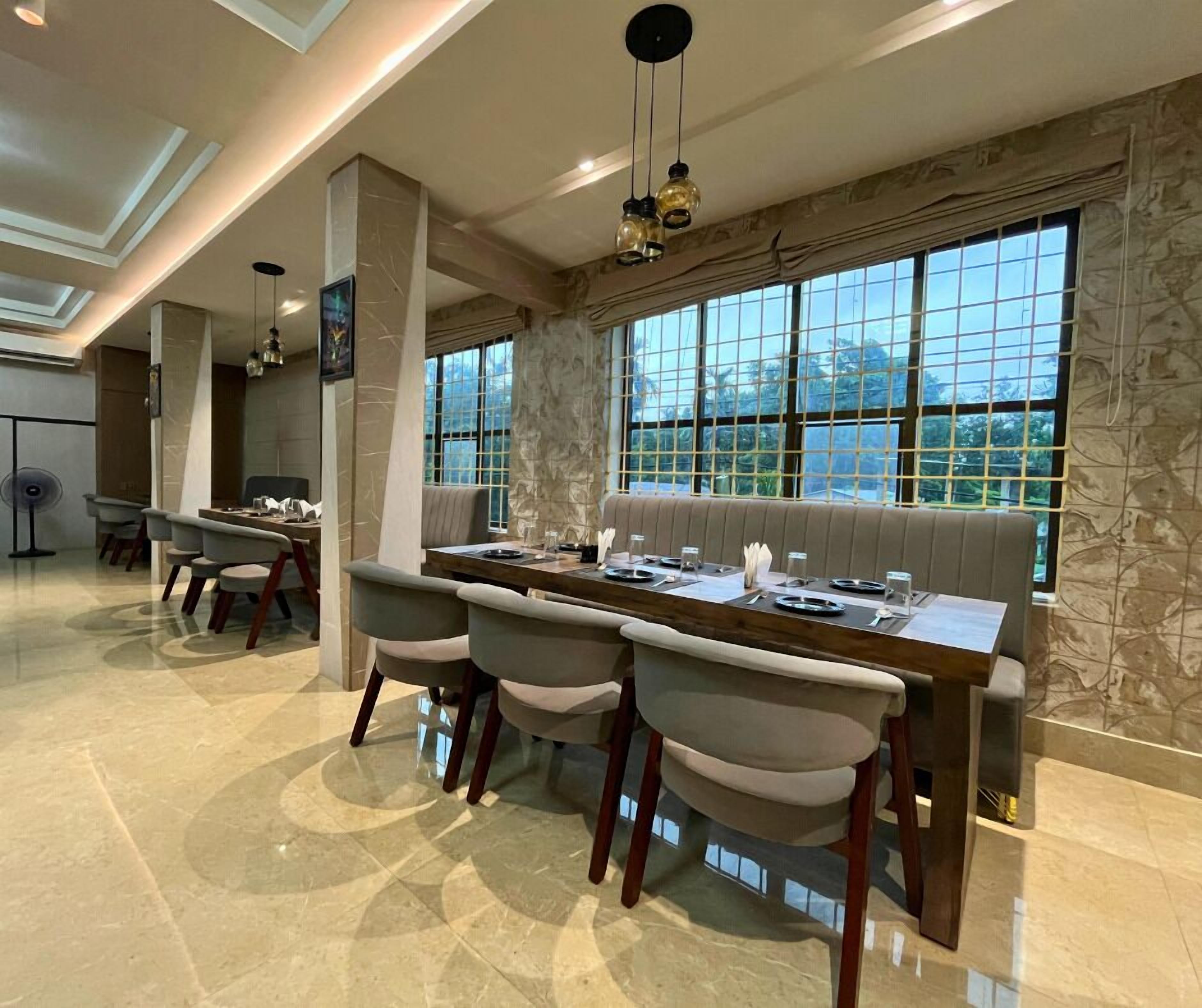 Un comedor moderno con una mesa larga, asientos acolchados y grandes ventanales que ofrecen vistas al exterior.