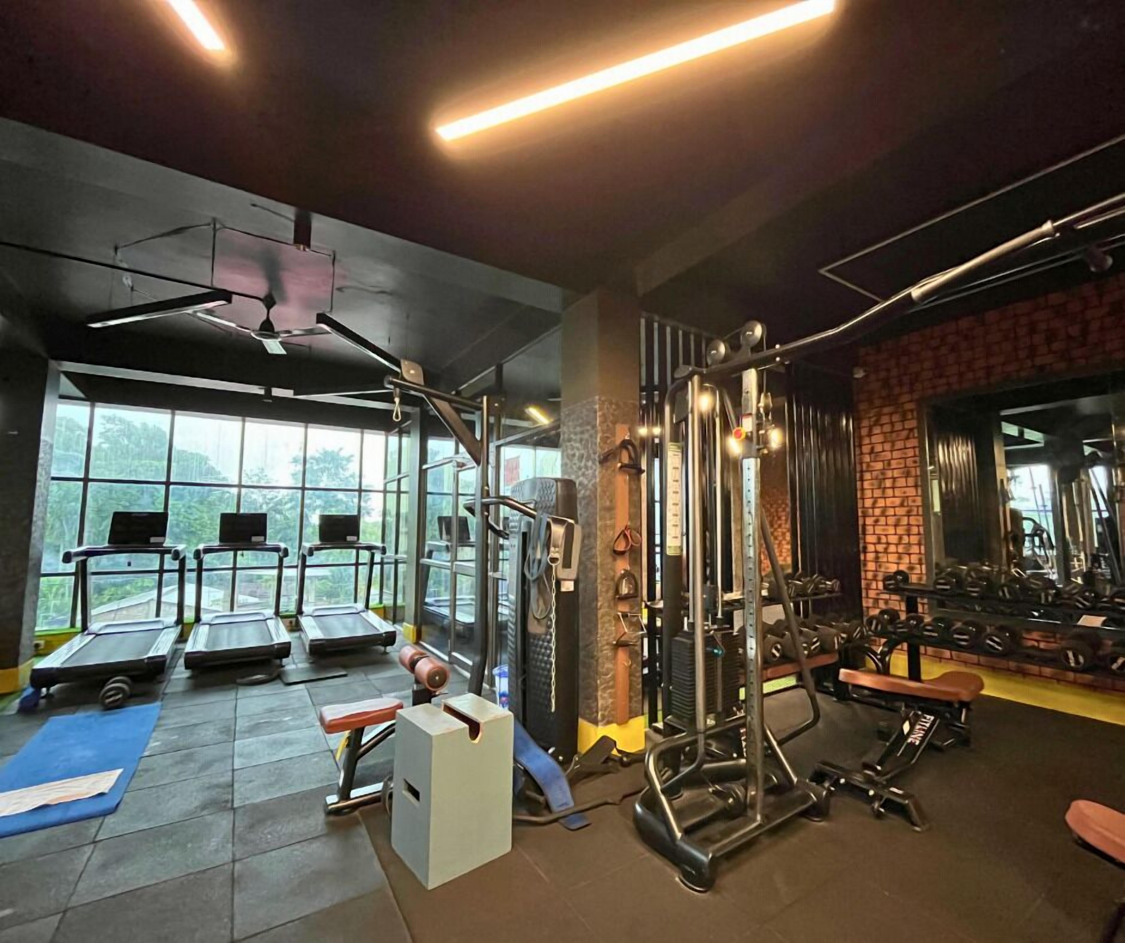 A gym with treadmills, weight machines, and a brick wall.