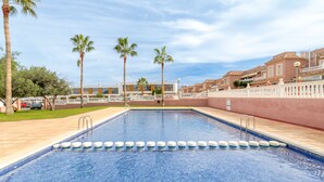A swimming pool with clear blue water, surrounded by palm trees and a white fence. - Holiday Home 'Bungalow Martina for 6 People' with Shared Pool, Wi-Fi and Air Conditioning (Santa Pola)