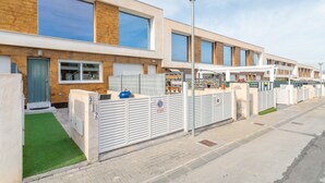 A modern building with large windows, a gated entrance, and a street lamp. - Holiday Home 'Bungalow Martina for 6 People' with Shared Pool, Wi-Fi and Air Conditioning (Santa Pola)