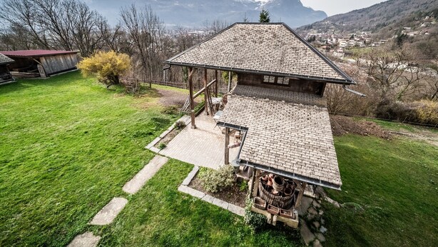 Un chalet rústico con techo inclinado, terraza de madera y vistas a montañas nevadas.