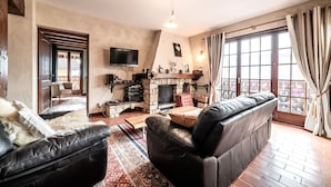 Una sala de estar con chimenea, sofá de cuero y televisor.