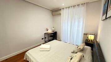 A neatly arranged bedroom with a bed, bedside tables, and a desk.