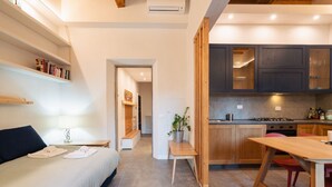 A modern hotel room with a bed, bedside table, lamp, and a view into the kitchen area. - Blu's house in Florence (Firenze)