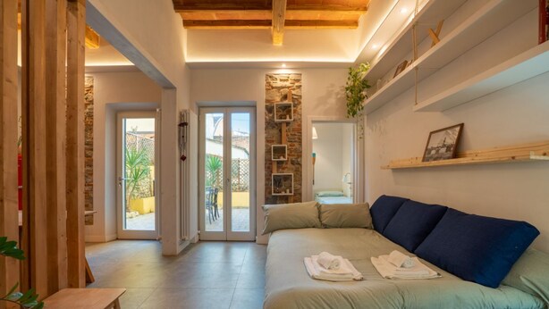 A cozy room with a bed, a wooden bench, a stone wall, and a view of the outside. - Blu's house in Florence (Firenze)