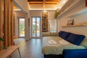 Quarto acolhedor com cama, um banco de madeira, parede de pedra e vista para o exterior.