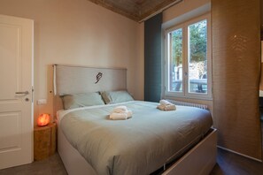 Quarto com cama, abajur, janela e porta.