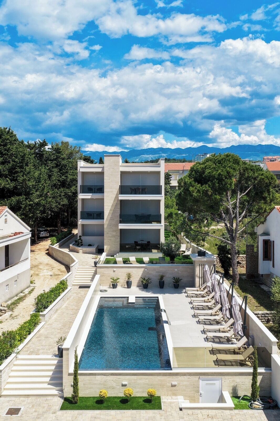 Ett modernt hotell med pool, utomhusservering och utsikt över bergen.