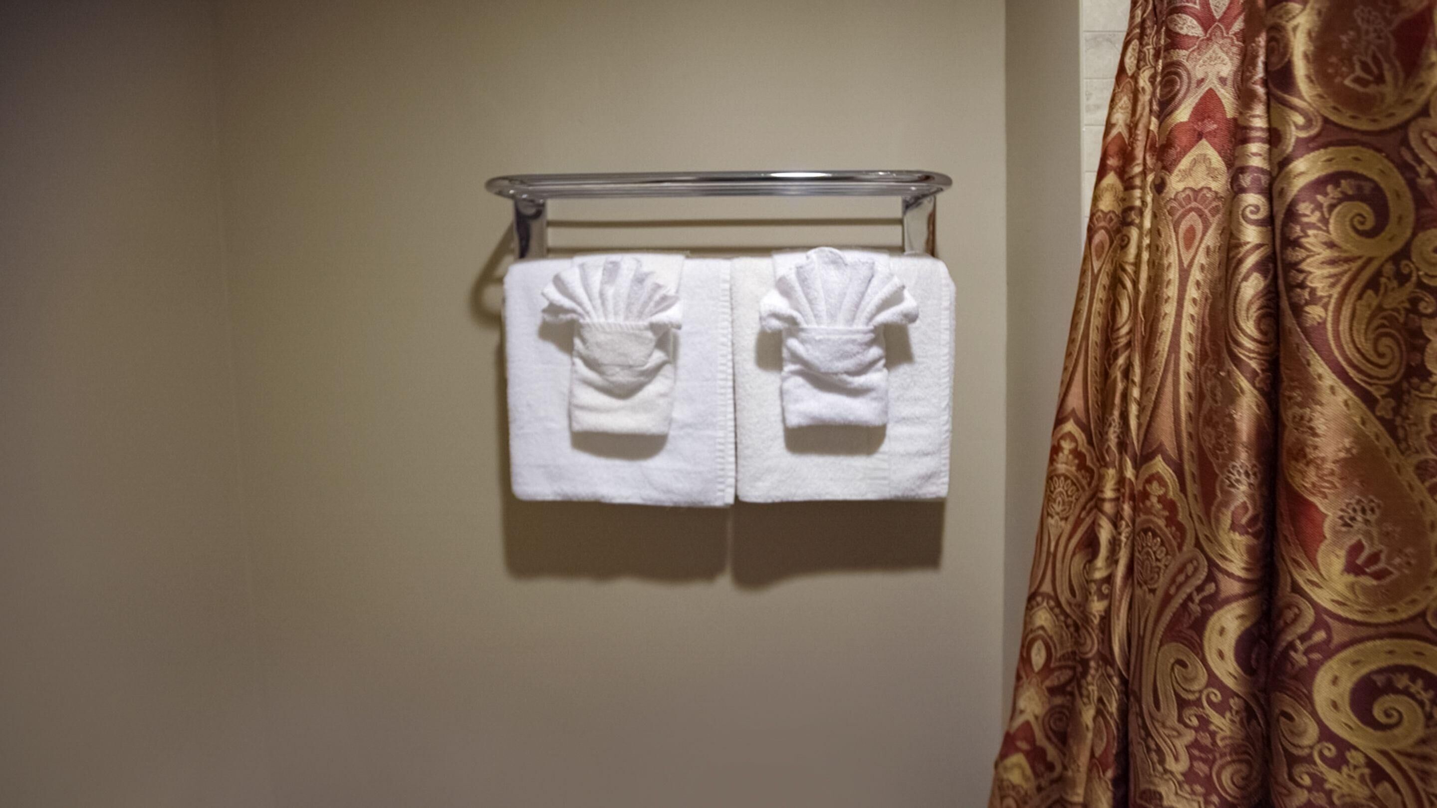 Une salle de bain avec un porte-serviettes sur lequel sont posées deux serviettes blanches.