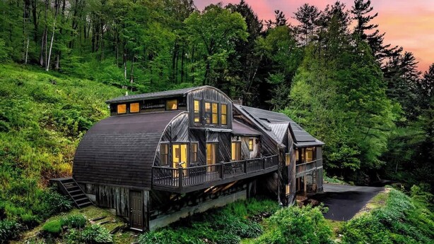A large, rustic cabin with multiple levels and a wrap-around porch, surrounded by dense forest. - Cedar Hill Lodge | 10 Min to Mt Snow w/Hot Tub (Wardsboro)