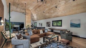 A spacious living room with a foosball table, a sectional sofa, and a dining area with a long table and chairs. - Cedar Hill Lodge | 10 Min to Mt Snow w/Hot Tub (Wardsboro)