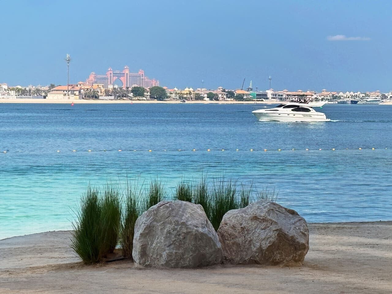 Eine Küstenlandschaft mit freiem Blick auf das Meer, einem Sandstrand und einem großen Gebäude im Hintergrund.