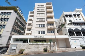 A multi-story hotel with a central entrance, balconies, and a stone facade.