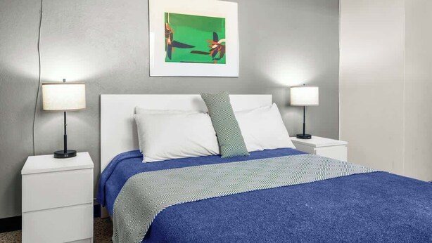 A hotel room with a bed, two bedside tables, and a wall-mounted picture.