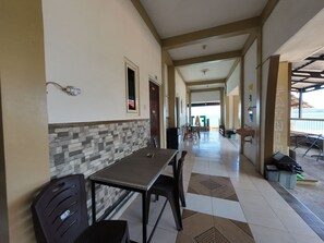 A corridor with a dining area featuring a table and chairs, a tiled floor, and a view of the sea. - FATHIN HOTEL BAWEAN SYARIAH (Sangkapura)