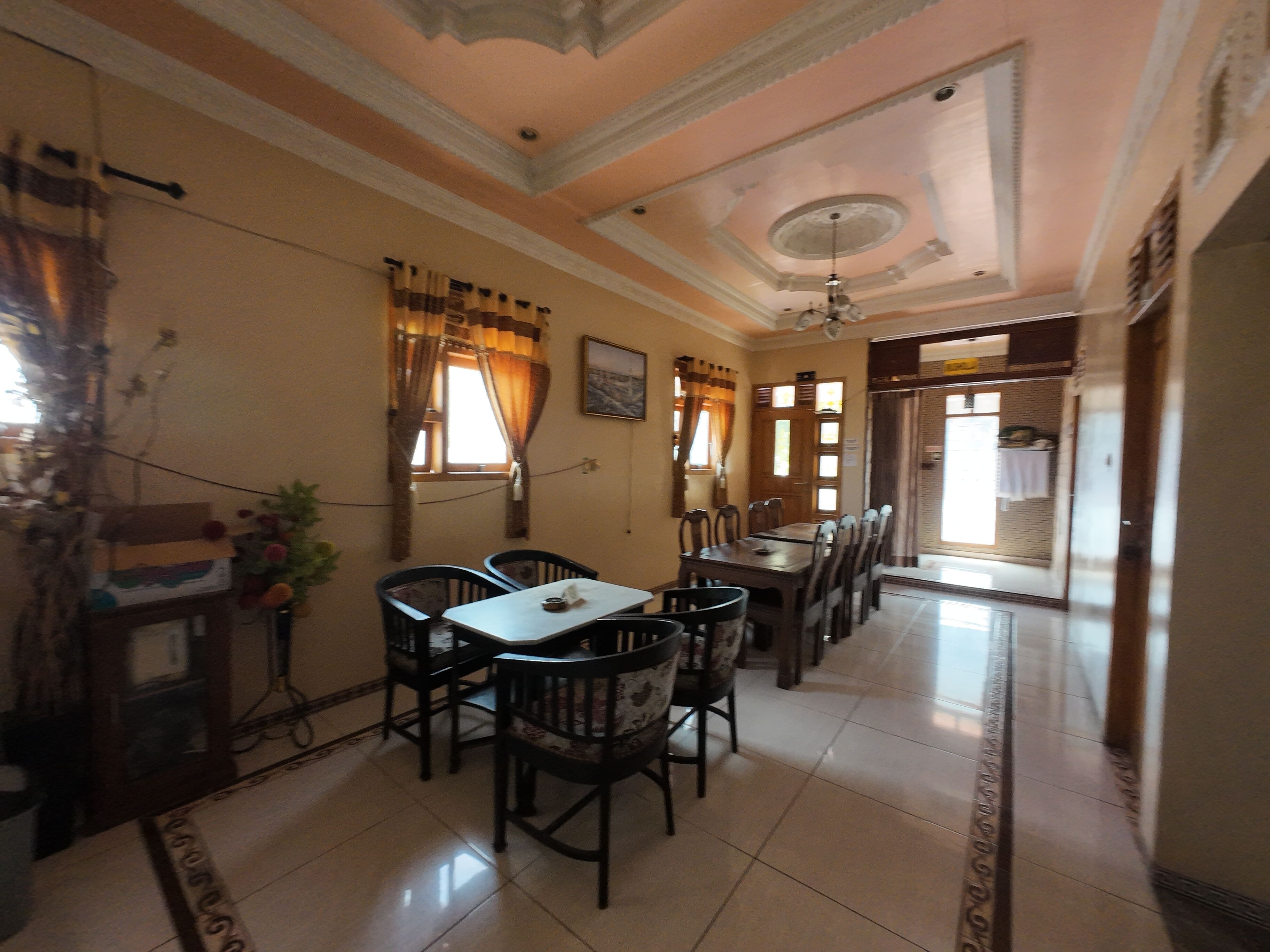 A dining area with a table and chairs, a ceiling fan, and a view of a hallway.