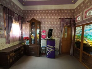A room with a wooden cabinet, a purple decorative item, and a wall with a patterned design.