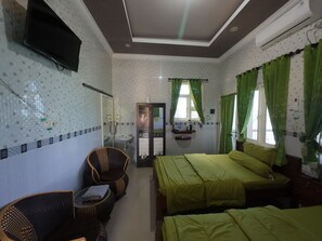A hotel room with a bed, a chair, a sink, and a television.