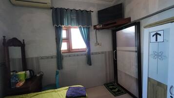 A room with a bed, a window with curtains, a mirror, a wardrobe, and a door with an arrow sign.