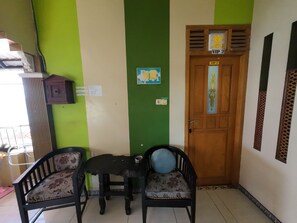 A room with a green and white wall, a wooden door with a 'VIP 2' sign, two chairs with floral upholstery, and a small table with a bowl. - FATHIN HOTEL BAWEAN SYARIAH (Sangkapura)