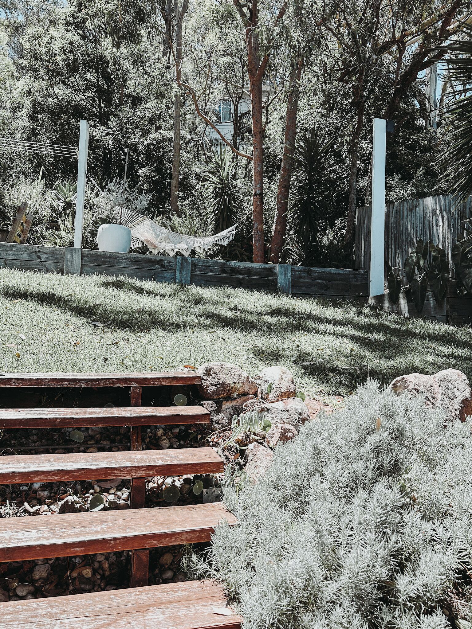 A wooden staircase leading up to a grassy area with a hammock and a hammock chair.