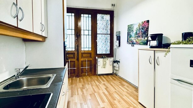 A kitchen with a sink, cabinets, a refrigerator, and a door leading to another room. - Modern Studio Stay Near Stadthalle (Vienna)