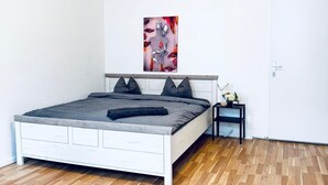 A bedroom with a white bed, grey bedding, a small bedside table with a lamp, and a wall-mounted artwork. - Modern Studio Stay Near Stadthalle (Vienna)