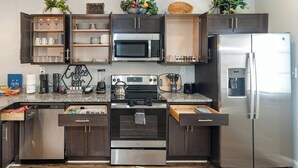Una cocina moderna con armarios de madera oscura, electrodomésticos de acero inoxidable y encimera de granito.