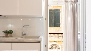 A modern kitchen with a sink, two potted plants, and a view of a balcony with a metal railing.