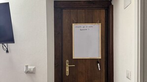 A wooden door with a whiteboard message, a wall-mounted light, and a power outlet. - B&B Nonna Cristina - Double Room 1 (Vecchio Abitato)