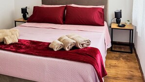 A neatly made bed with red and pink bedding, a wooden headboard, and two bedside tables with lamps. - B&B Nonna Cristina - Double Room 1 (Vecchio Abitato)