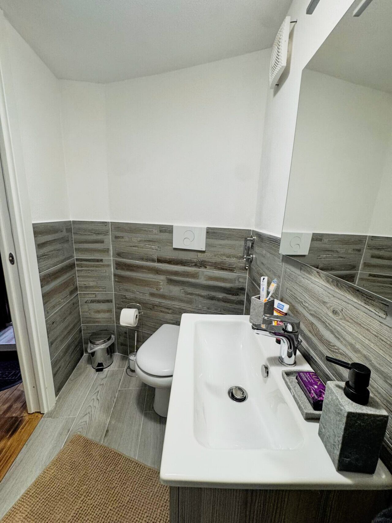 A modern bathroom with a white sink, a toilet, and a mirror.