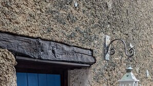 Un mur de pedra rústic amb una porta blava i un fanal blanc.