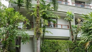A multi-story building with balconies, surrounded by lush greenery and palm trees. - Elegant Beachfront 3BR Condo at Pearl of Naithon (Sa Khu)