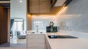 A modern kitchen with a built-in stove, a sink, and a countertop. - Beachfront 1501 2BR at Wyndham Naithon Phuket (Sa Khu)