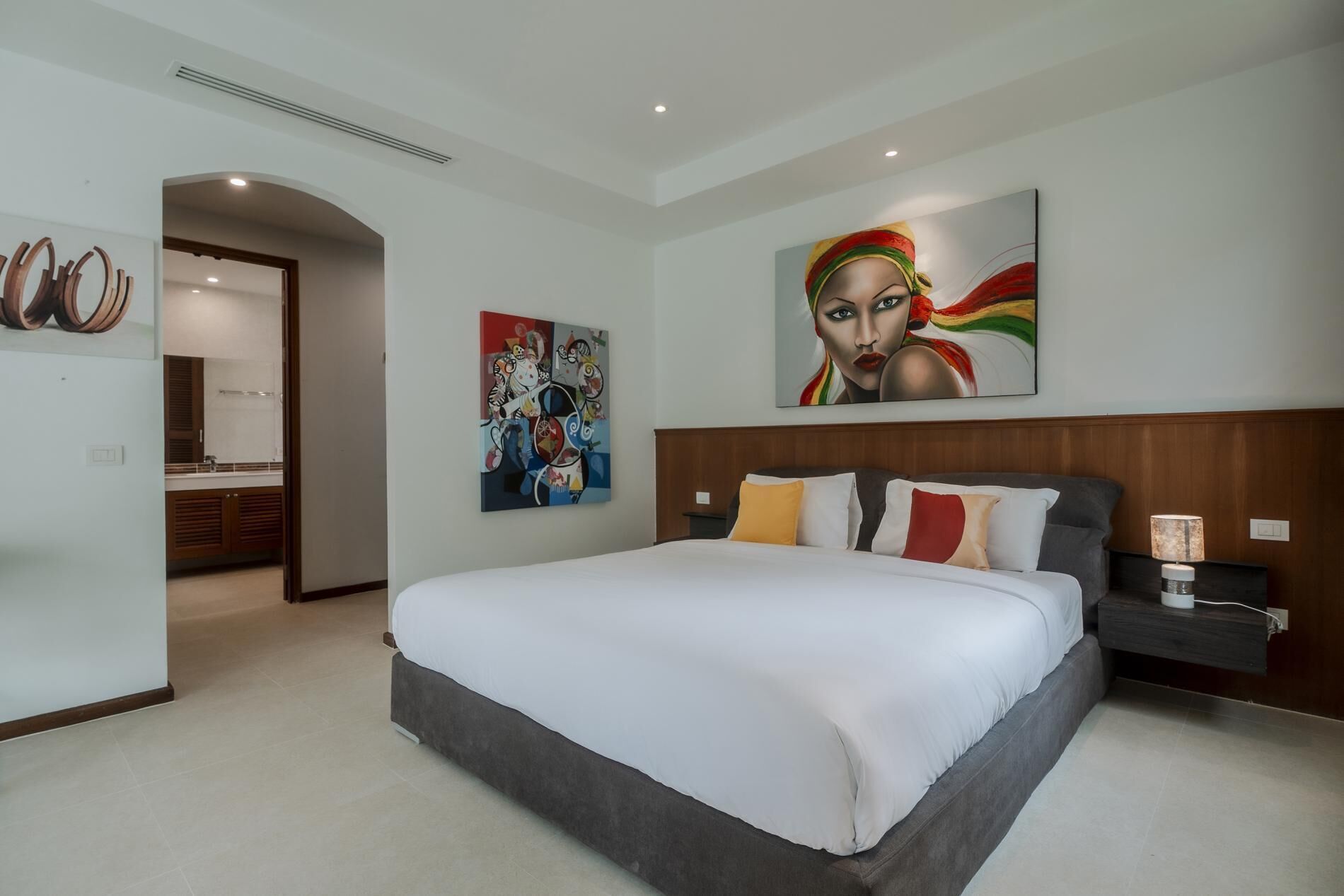 Una camera da letto moderna con un letto grande, una testiera in legno e due quadri appesi al muro.