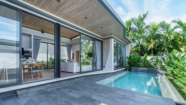 Een modern huis met een zwembad, grote glazen deuren en een terras.