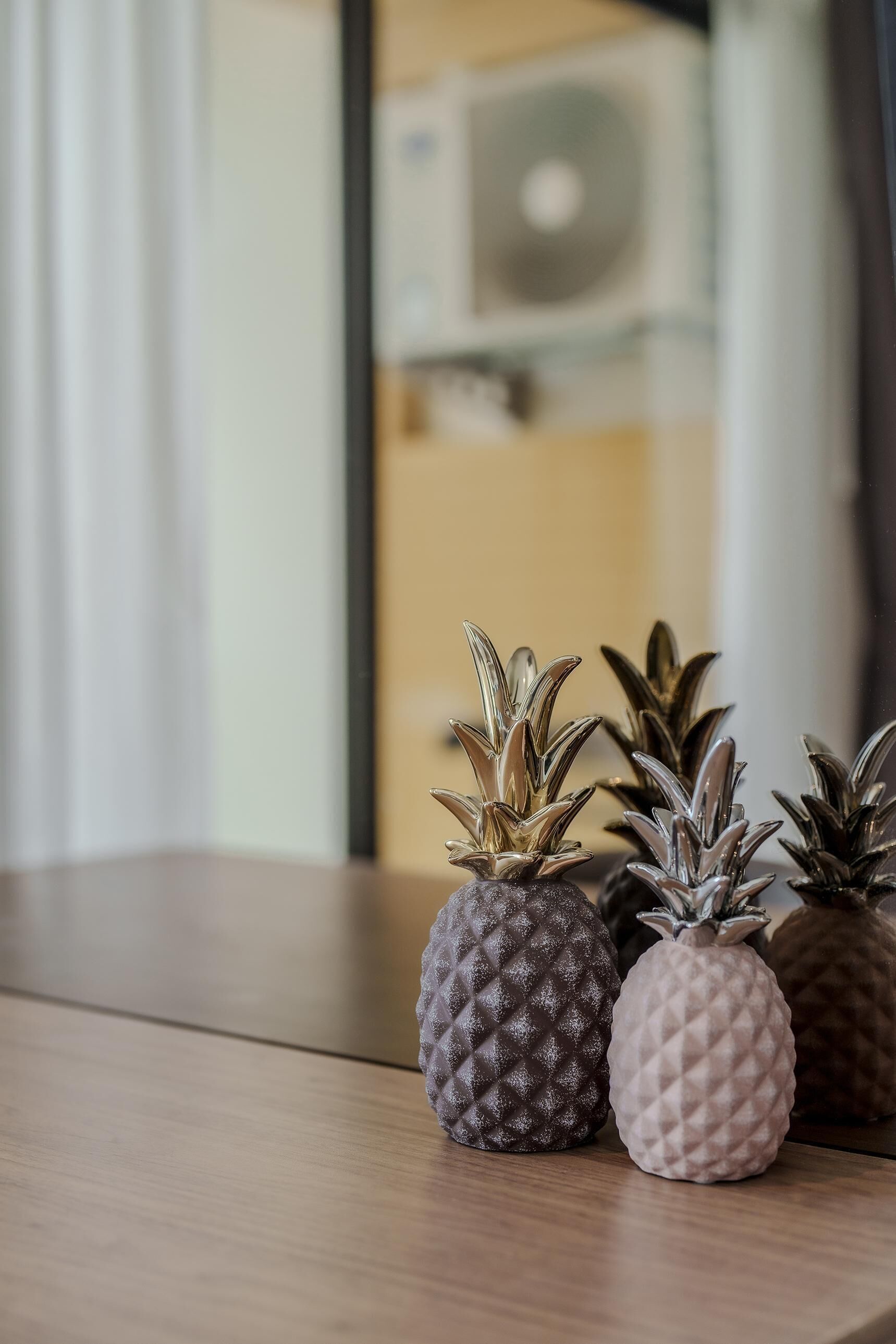 Ett träbord med fyra vaser i form av ananas, alla med olika färger och en tydlig ytstruktur.