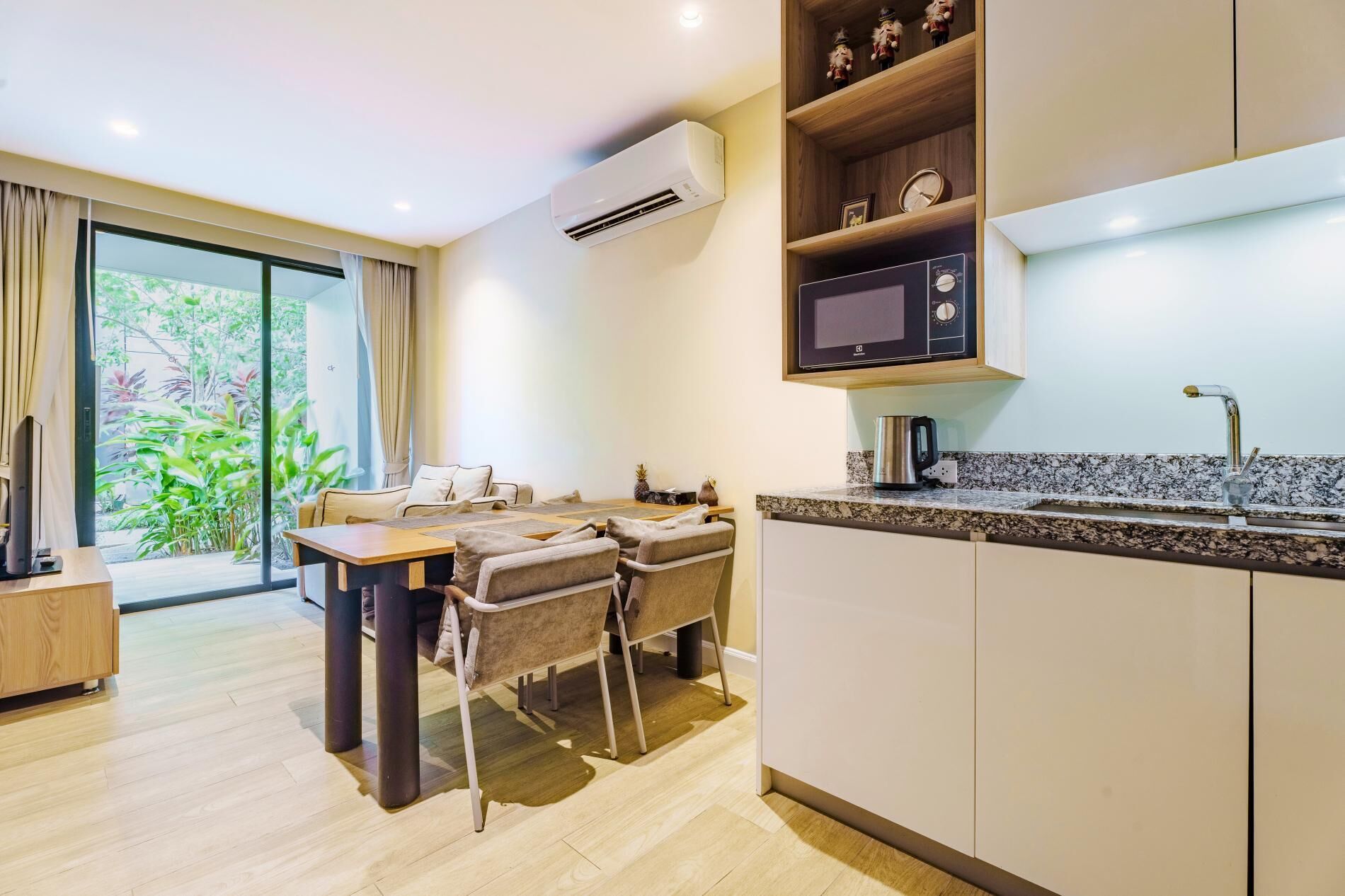 A modern kitchen with a built-in microwave, a coffee maker, and a sink. There is a dining area with a table and chairs.