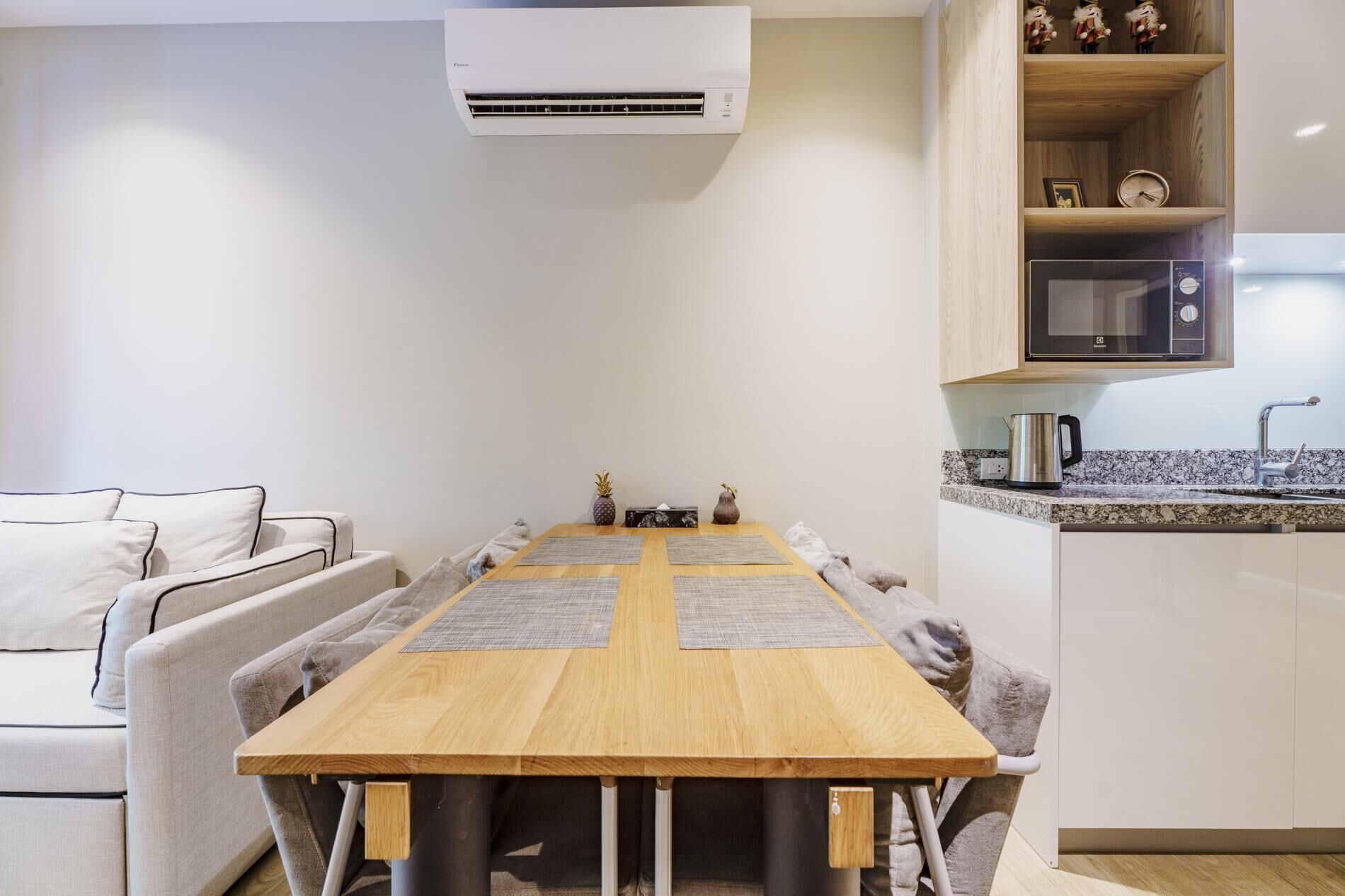 Una cocina moderna con una mesa de comedor de madera, un microondas empotrado y una cafetera.