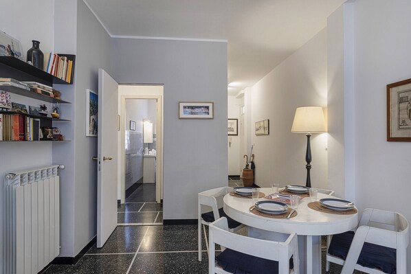 A dining area with a round table set for four, white chairs, and a white radiator on the left. - S Margherita Harbour Apartment by Wonderful Italy (Santa Margherita Ligure)